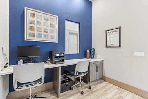 A blue wall with a white chair and a computer on a desk.