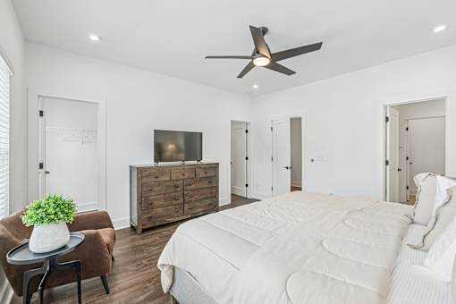 A bedroom with a large bed, a dresser, and a ceiling fan.
