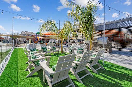 A row of white chairs are lined up on a green lawn.