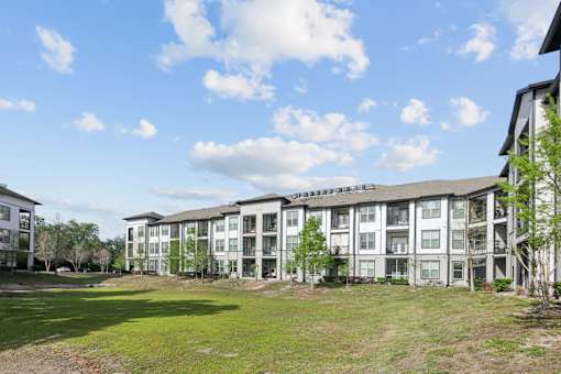 A large apartment complex with a grassy area in front.