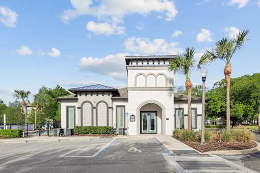 A white building with a black roof and palm trees in front.