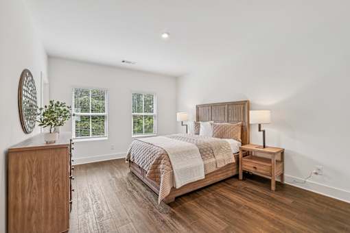 A bedroom with a large bed, wooden furniture, and a plant on a dresser.