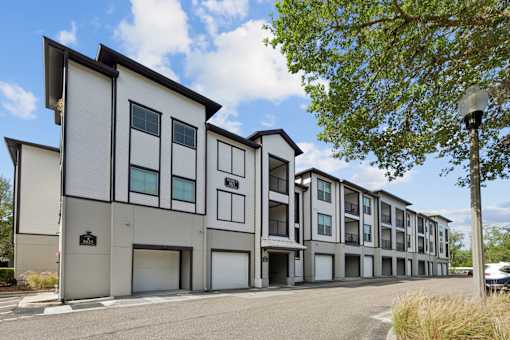 A modern apartment building with a parking lot in front.