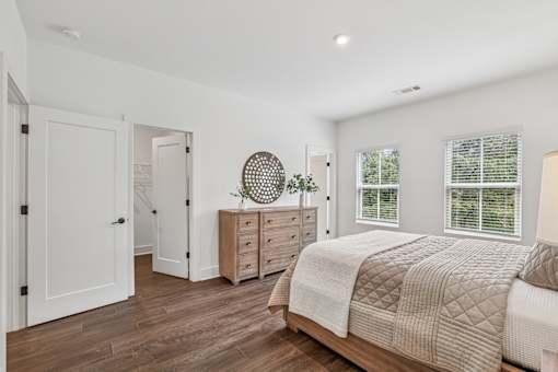 A bedroom with a bed, dresser, and mirror.