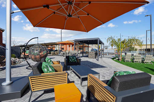 A patio with orange umbrellas and wooden chairs.