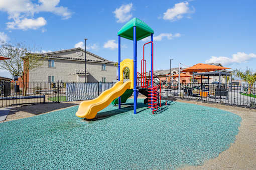 A playground with a yellow slide and a blue and green top.