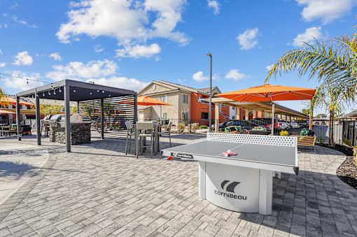 A white table tennis table with the brand name "Camilleau" on it is placed on a patio.