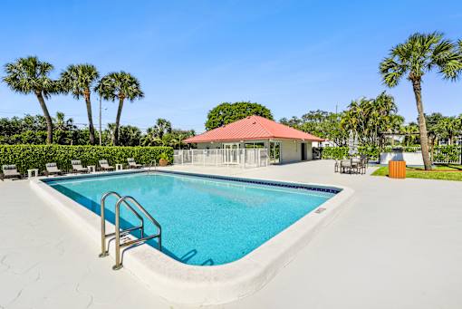 A swimming pool with a red roofed building in the background.