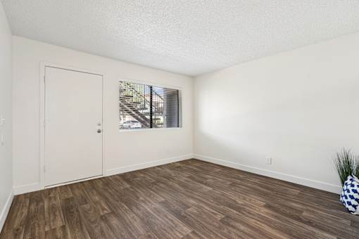 A room with a wooden floor and a door leading to a balcony.