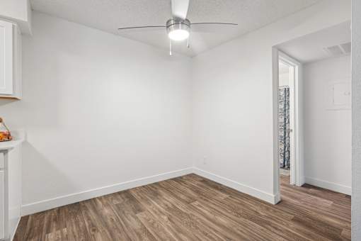 A room with a ceiling fan and wooden flooring.