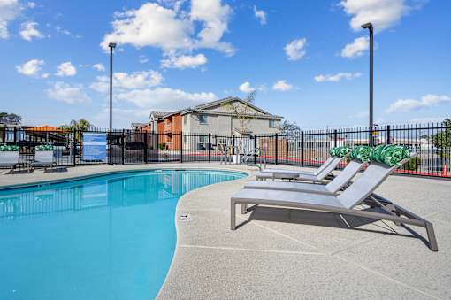 A pool with a sun lounger and a building in the background.