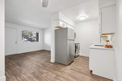 A kitchen with a refrigerator, oven, and sink.