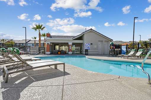 A pool with sun loungers and a building in the background.