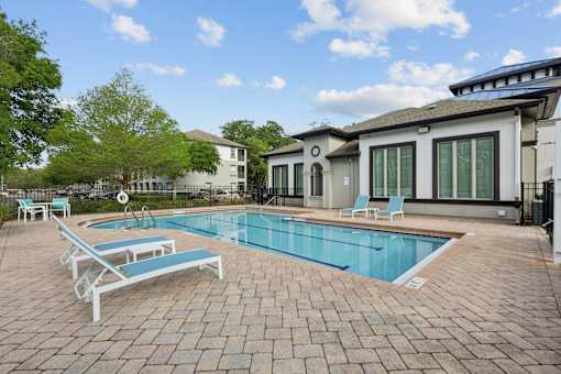 A pool with a blue tiled edge and a white sunbed.