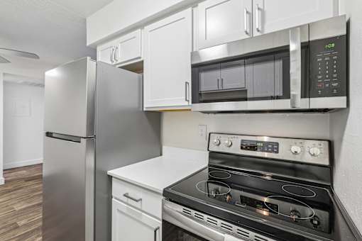 A modern kitchen with a stainless steel refrigerator, microwave, and oven.