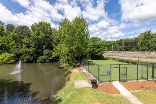 a tennis court overlooking a pond with a fountain