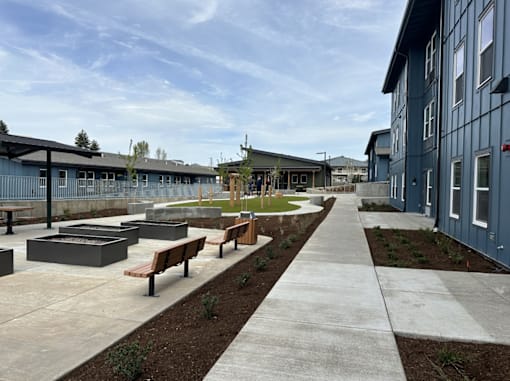 A long concrete walkway leads to a building with a blue exterior.