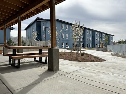 A modern building with a wooden pergola and bench in front.