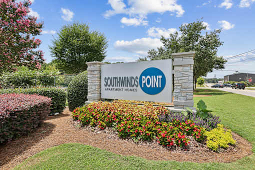 A sign for Southwinds Point Apartment Homes is surrounded by flowers and greenery.