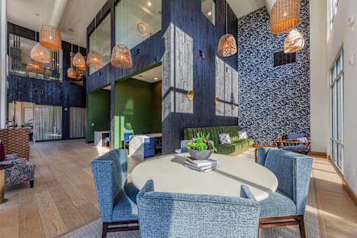 a communal area with a round table with blue chairs and a green couch in the background