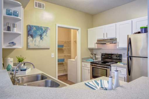 Duluth, GA Apartments – Grande Club – A kitchen with a refrigerator, sink, and cabinets.