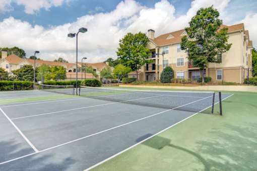 Apartments in Duluth, GA 30096 for Rent – Grande Club - A tennis court is surrounded by apartment buildings.