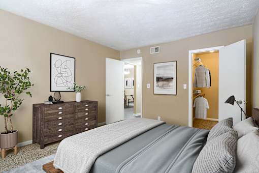 A bedroom with a large bed and a dresser with a plant on top.