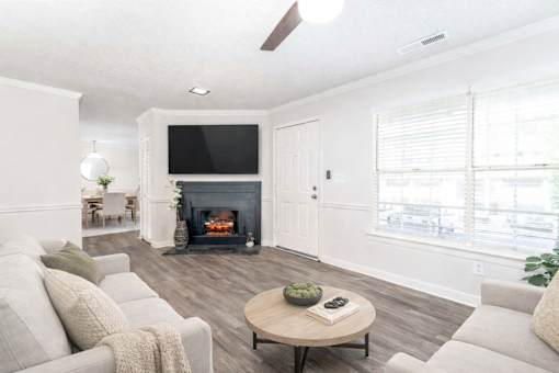 Spacious living room with fireplace, wood-style flooring, and natural light at Sugar Creek Apartments in Winston Salem NC
