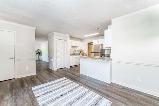 Open concept apartment kitchen and living area at Sugar Creek Apartments in Winston Salem NC with stainless appliances and wood style flooring