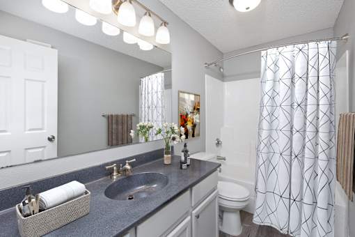 A bathroom with a white toilet, sink, and shower curtain.