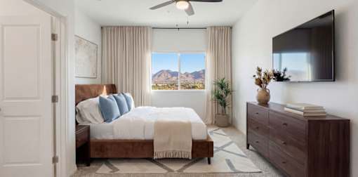 Elegant bedroom with a stylish bed, mountain views through a large window, and tasteful decor featuring modern accents.