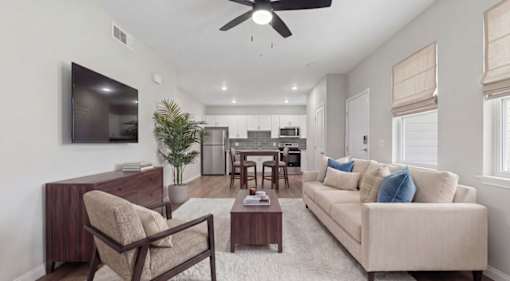 Modern open-concept living room with cozy neutral tones, stylish furniture, and sleek kitchen in the background at Summit on Boulder Apartments near Las Vegas in Henderson NV