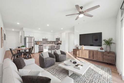 A modern living room with a grey sofa, a white coffee table, and a television on a wooden cabinet.