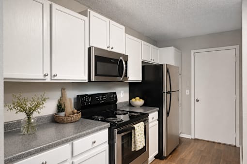 Virtually staged kitchen at Summit Townhomes in Burnsville, MN, with white cabinets and stainless steel appliances.