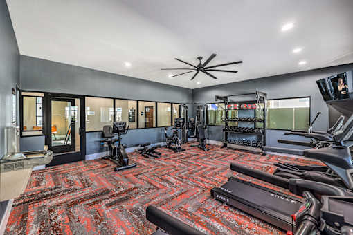 Modern fitness center at Summit on Boulder Apartments with state-of-the-art gym equipment, vibrant flooring, and spacious layout for an energizing workout experience.