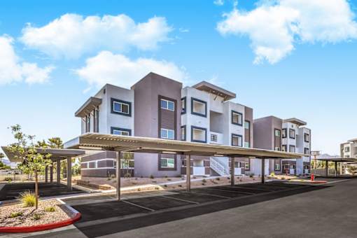 Modern apartment complex with stylish architecture, featuring covered parking and beautifully landscaped surroundings under a clear blue sky at Summit on Boulder Apartments.