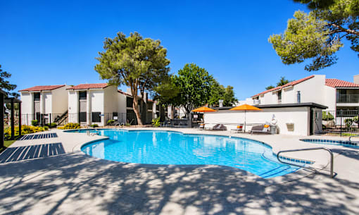 Outdoor swimming pool surrounded by mature trees at Haven at Lone Mountain apartments in Las Vegas