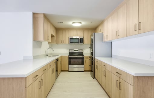 Apartments in Santa Monica CA for Rent - San Vicente Tower - Modern Kitchen with Stainless Steel Appliances, White Countertops, and Light Wood-Style Cabinetry