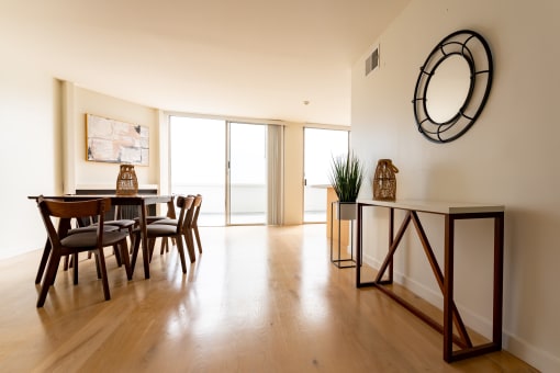 Santa Monica, CA Apartments near LAX - San Vicente Tower - Dining Area on Hardwood Flooring with White Walls, Mounted Mirror, Table with Chairs, and Balcony Access