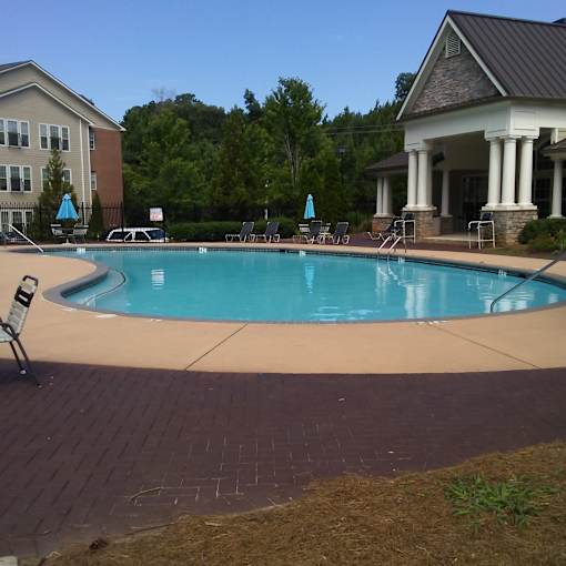 A small pool with a brick border and a building in the background.
