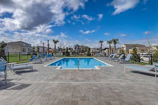 A swimming pool surrounded by lounge chairs and palm trees.