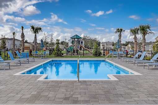 A large swimming pool surrounded by lounge chairs and palm trees.