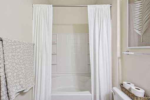 Clean full bathroom with white shower-tub combo and linen storage at Tattersall Village Apartments in Hinesville