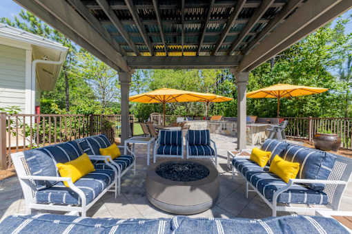 Outdoor seating area with a fireplace at The Sanctuary at 331 apartment complex in Santa Rosa Beach, Florida, featuring comfortable chairs arranged around the fire.