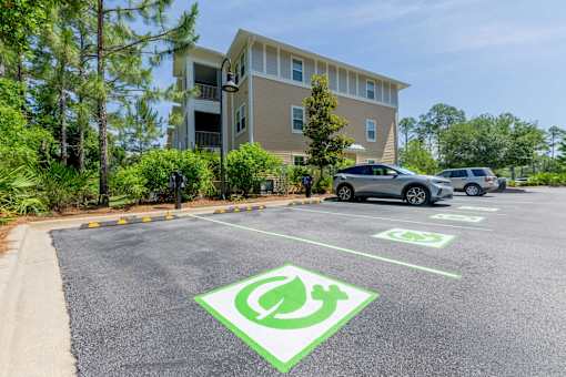 A parking lot with a green electric car charging station sign.