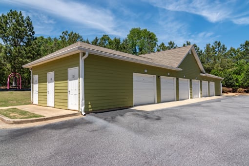 a row of garages in front of a grassy area with trees in the background