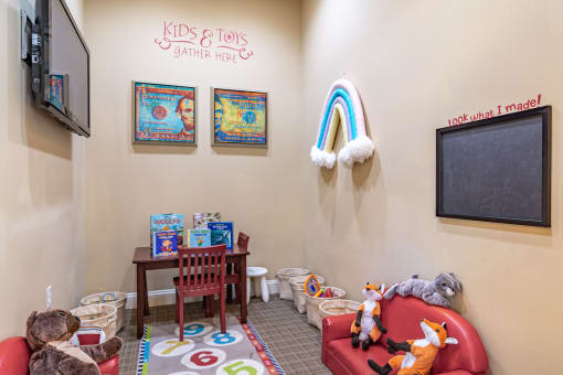 Pet-Friendly Apartments in Opelika, AL – The Crossings of Opelika -  a childs play area with toys and a chalkboard on the wall