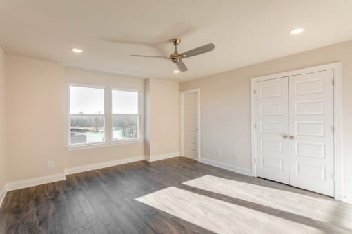 Apartments in Gallatin for Rent - The Gardens at Preston Park - Bedroom with Wood-Style Flooring, Ceiling Fan, and Large Windows