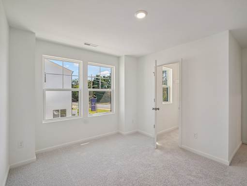 Large bedroom with windows and plush carpeting in The Maple 3-bedroom townhomes Raleigh NC