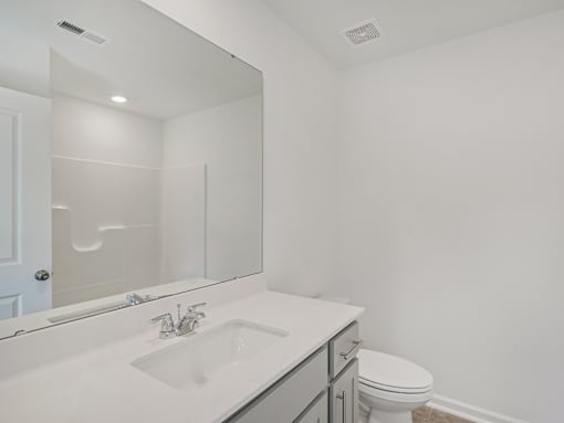 “Modern bathroom with granite vanity and storage at The Maple Raleigh townhomes